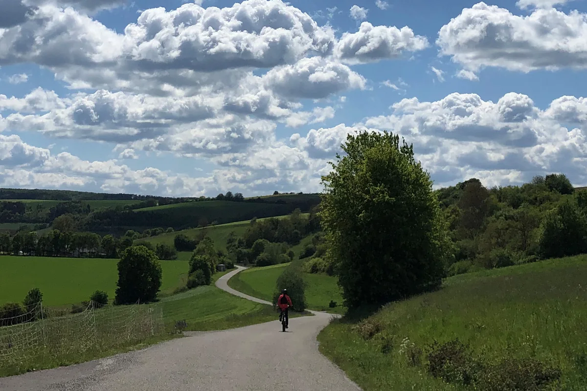Radfahrer auf einem Weg durch die Hügellandschaft des Taubertals